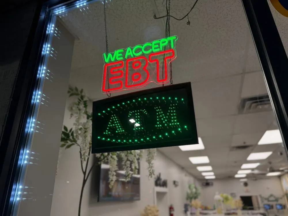 Neon We Accept EBT and ATM signs in the storefront window